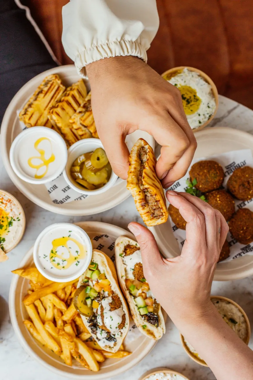 Mesa farta de comida israelense no Bubbeleh: homus, pastas, pão pita e saladas